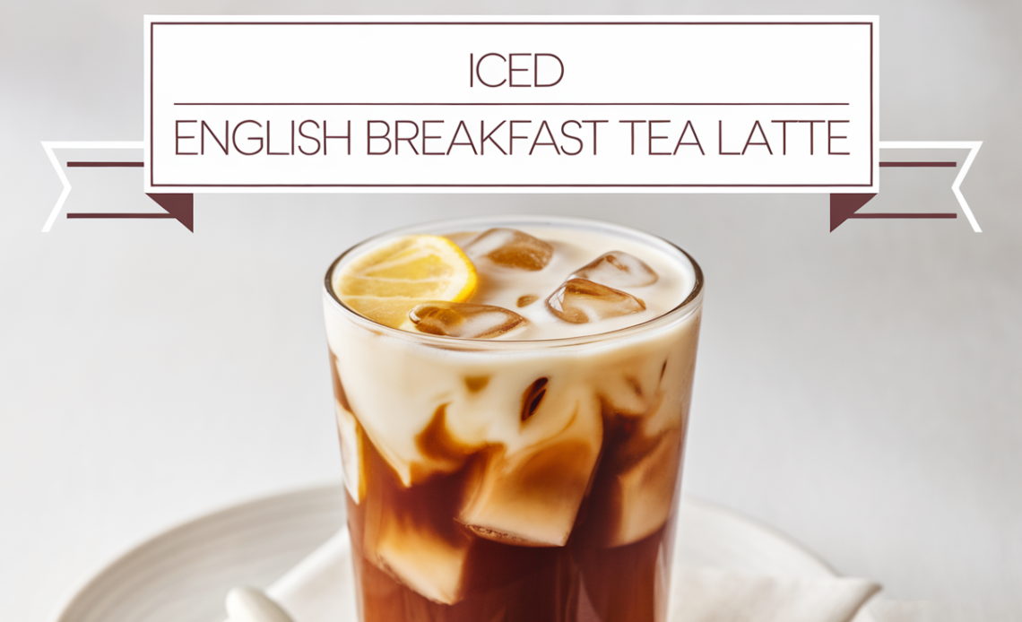 A tall glass of iced English Breakfast tea latte with a creamy layer of frothy milk, served with a slice of lemon and ice cubes.
